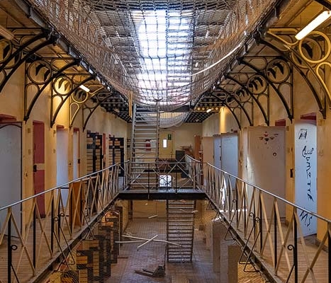 03.10.–15.11.26<br> Stadtmuseum: Gefängnisarchitektur »Jenseits der Mauern« Innenansicht der alten Justizvollzugsanstalt Münster mit Zellentüren, umlaufenden Galerien und vergitterter Dachkonstruktion, fotografiert von Chris Schwemmer