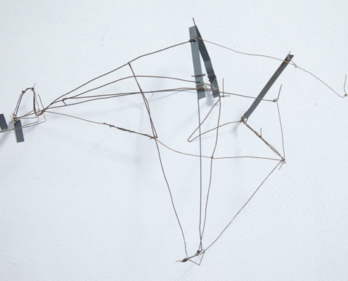 03.10.–01.11.26<br>no cube: Sabina Flora, Jae Jin Park und Werner Ryschawy Filigranes Drahtobjekt von Werner Ryschawy an einer weißen Wand im no cube Münster