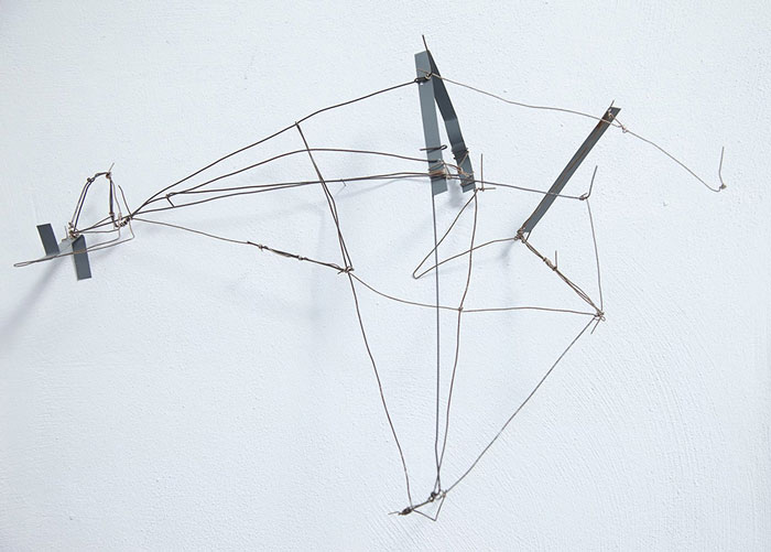 03.10.–01.11.26<br>no cube: Sabina Flora, Jae Jin Park und Werner Ryschawy Filigranes Drahtobjekt von Werner Ryschawy an einer weißen Wand im no cube Münster