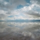 Fotografie „Near Highway 80“ von Trevor Paglen aus dem Jahr 2024: Eine weite, spiegelnde Wasserfläche reflektiert einen wolkenreichen Himmel. Am Horizont erstreckt sich eine schmale dunkle Landschaftslinie.